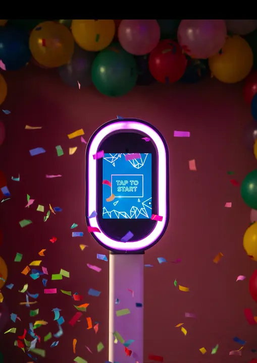 The MoPhotos MoFun booth glowing with a pink neon ring and confetti