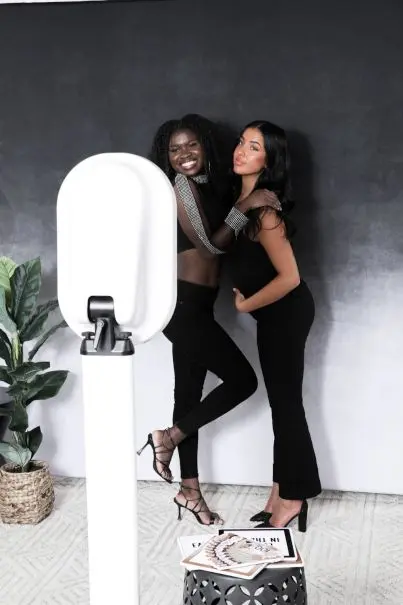 Two guests in black outfits posing beside the booth