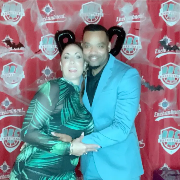 A couple in a teal suit and green dress posing at a Halloween party