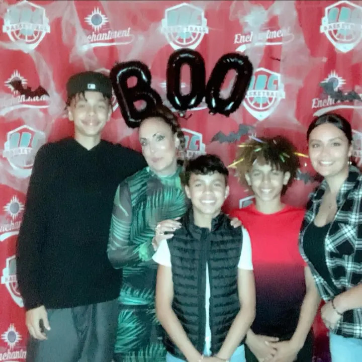 A family smiling together under BOO balloons