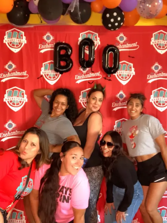 A group of women posing together under BOO balloons